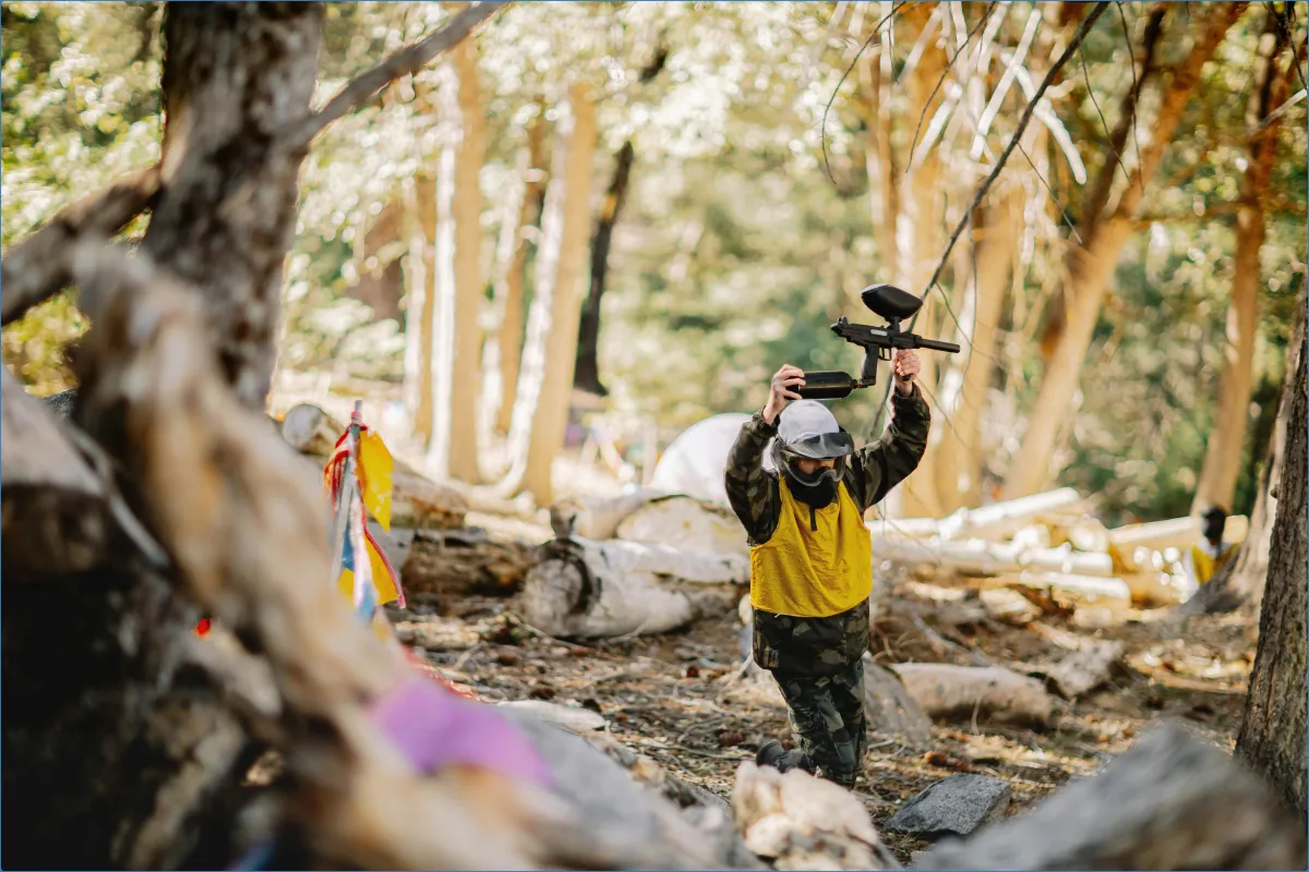 Person playing paintball in a forest.