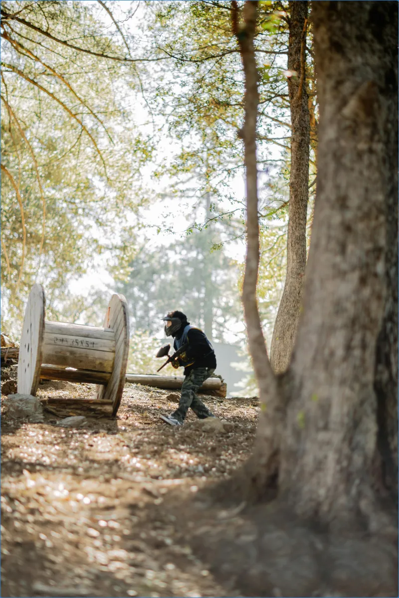 Person playing paintball in a wooded area