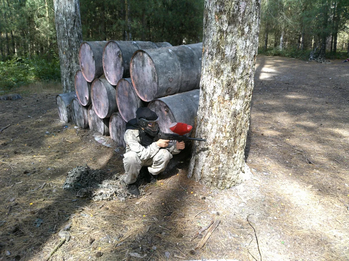 Person playing paintball hiding behind a tree