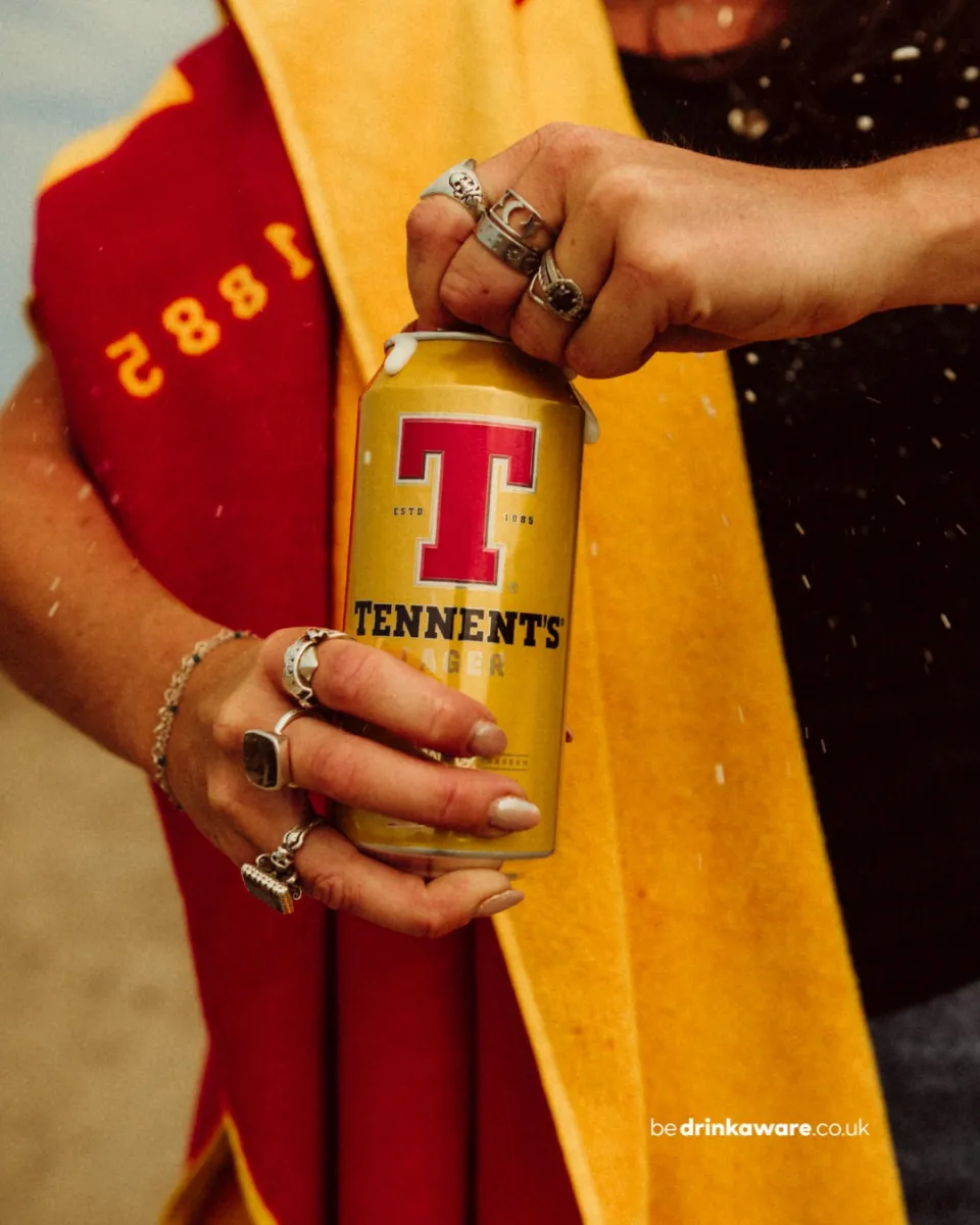 Person opening a can of Tennent's Lager.