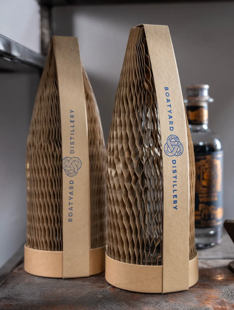 Two bottles in cardboard packaging on a shelf.