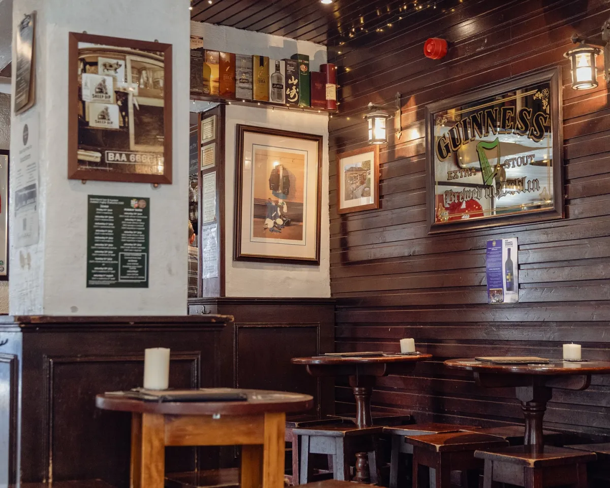 Cozy pub interior with wooden tables and Guinness sign.