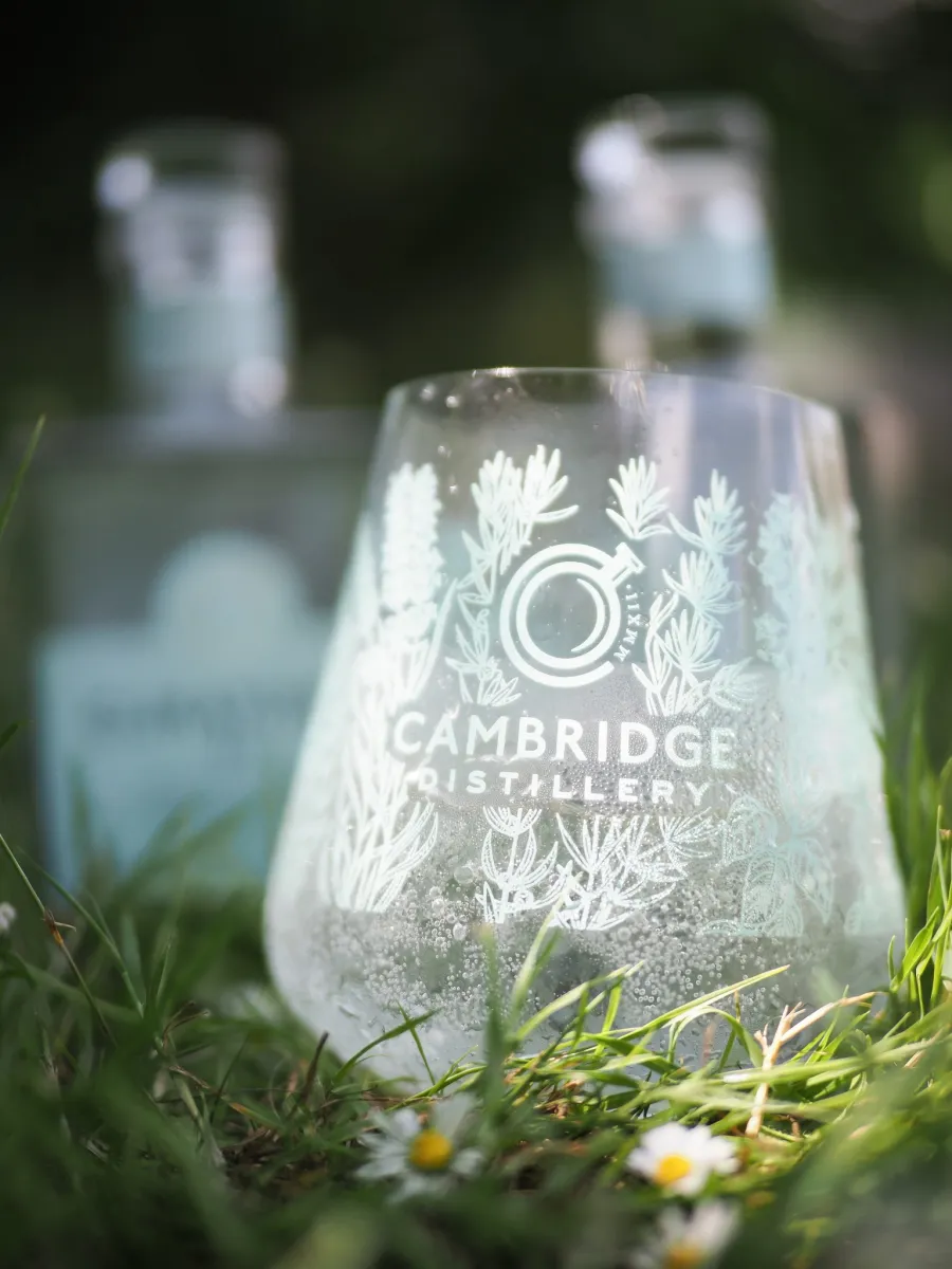 Cambridge Distillery glass on grass with bottles in background