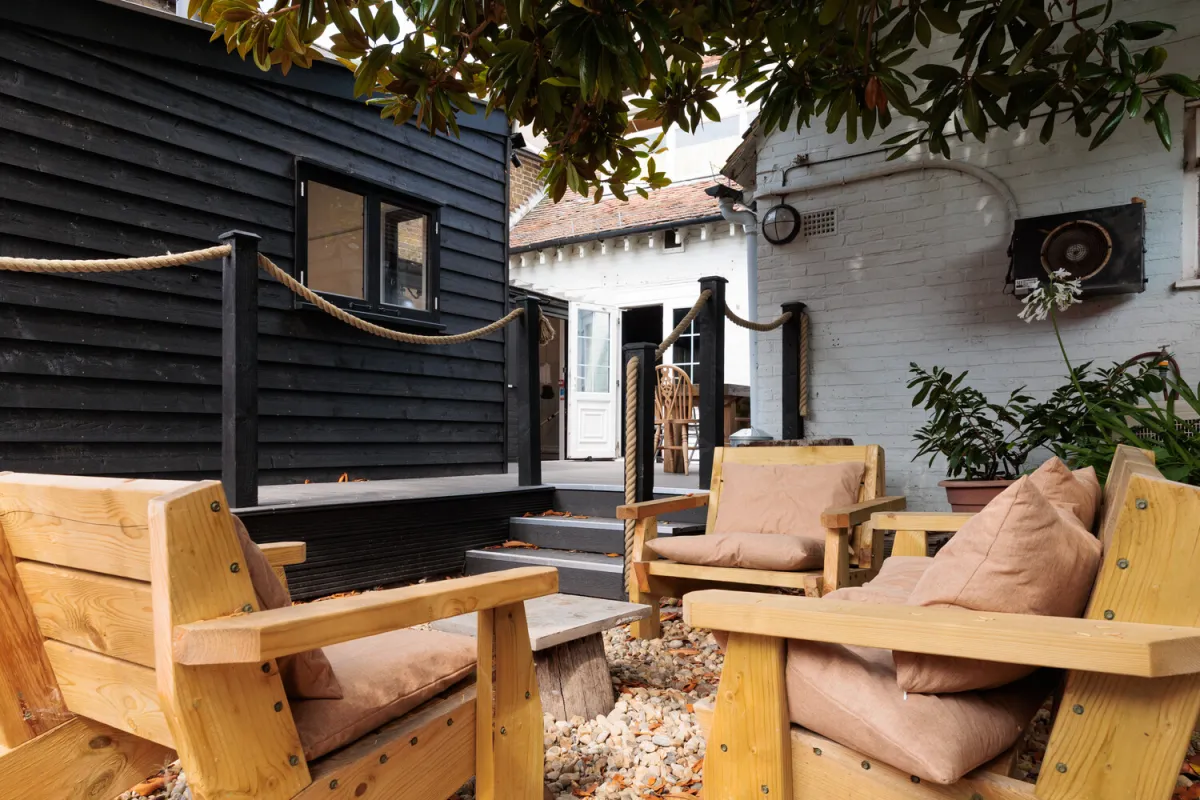 Outdoor seating area with wooden chairs and cushions.
