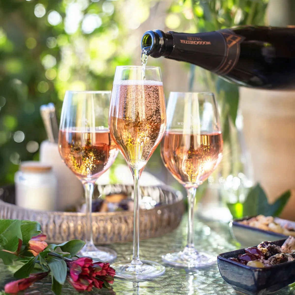Pouring rose champagne into glasses outdoors